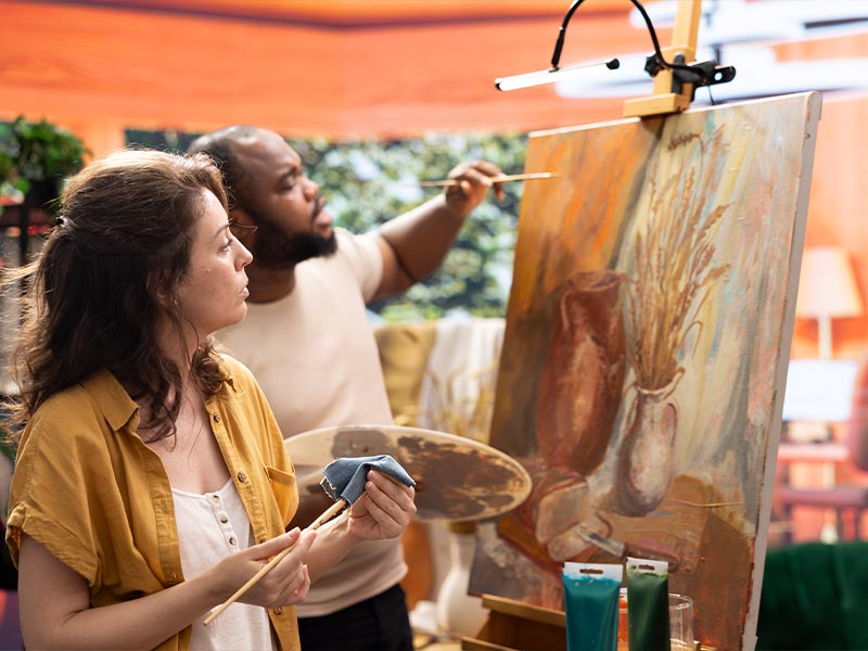 Corporate team building art workshop in Dubai with We Love Art - employees collaborating on paintings while building stronger workplace connections